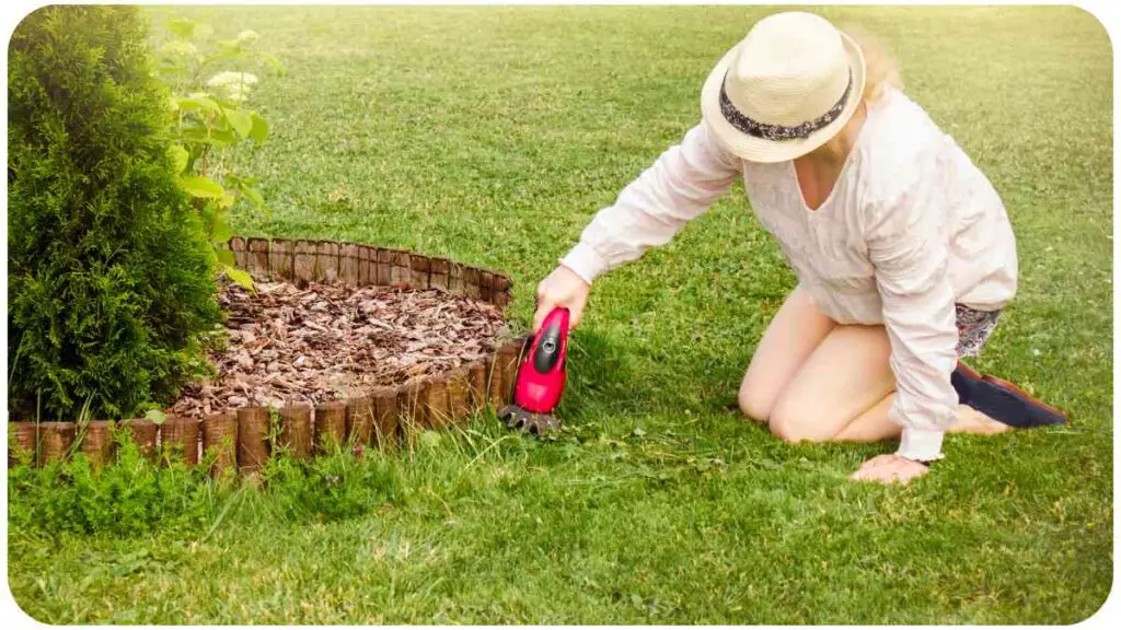 a person in a hat is trimming grass with a weed eater