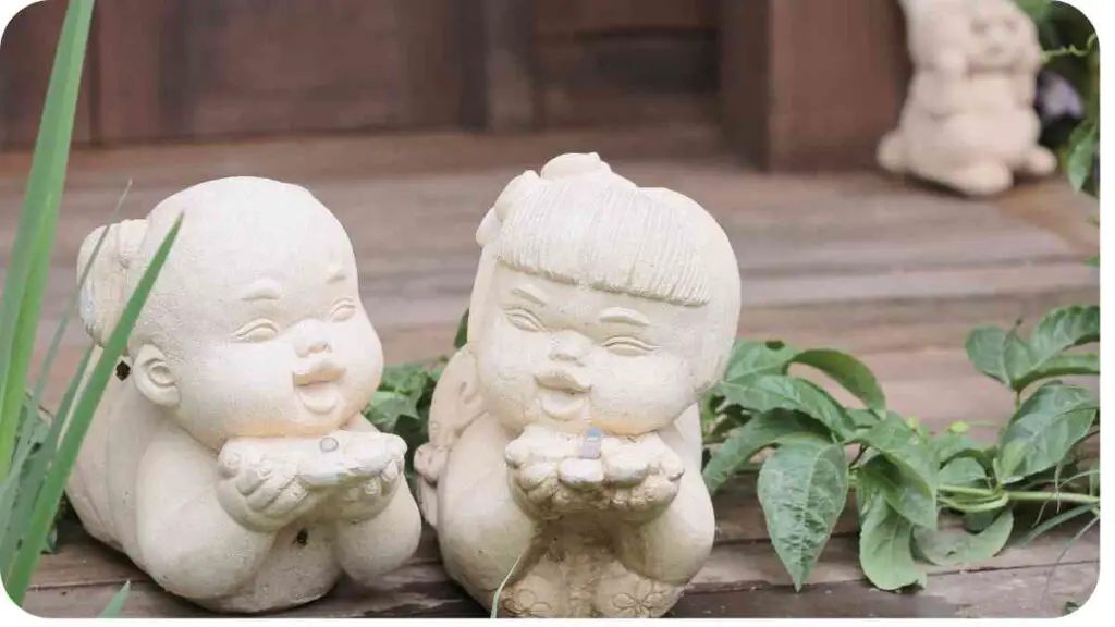 two statues of babies sitting on the ground next to each other