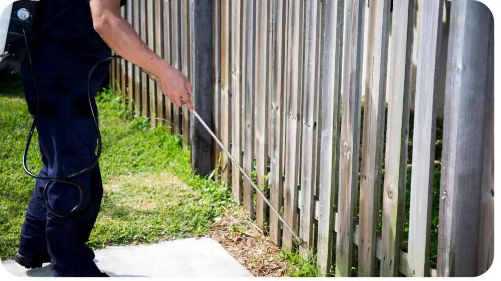 a person using a sprayer to clean a fence