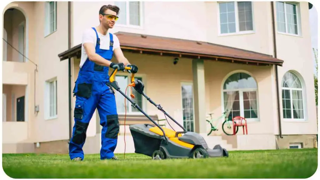 A person in overalls mowing the lawn in front of a house